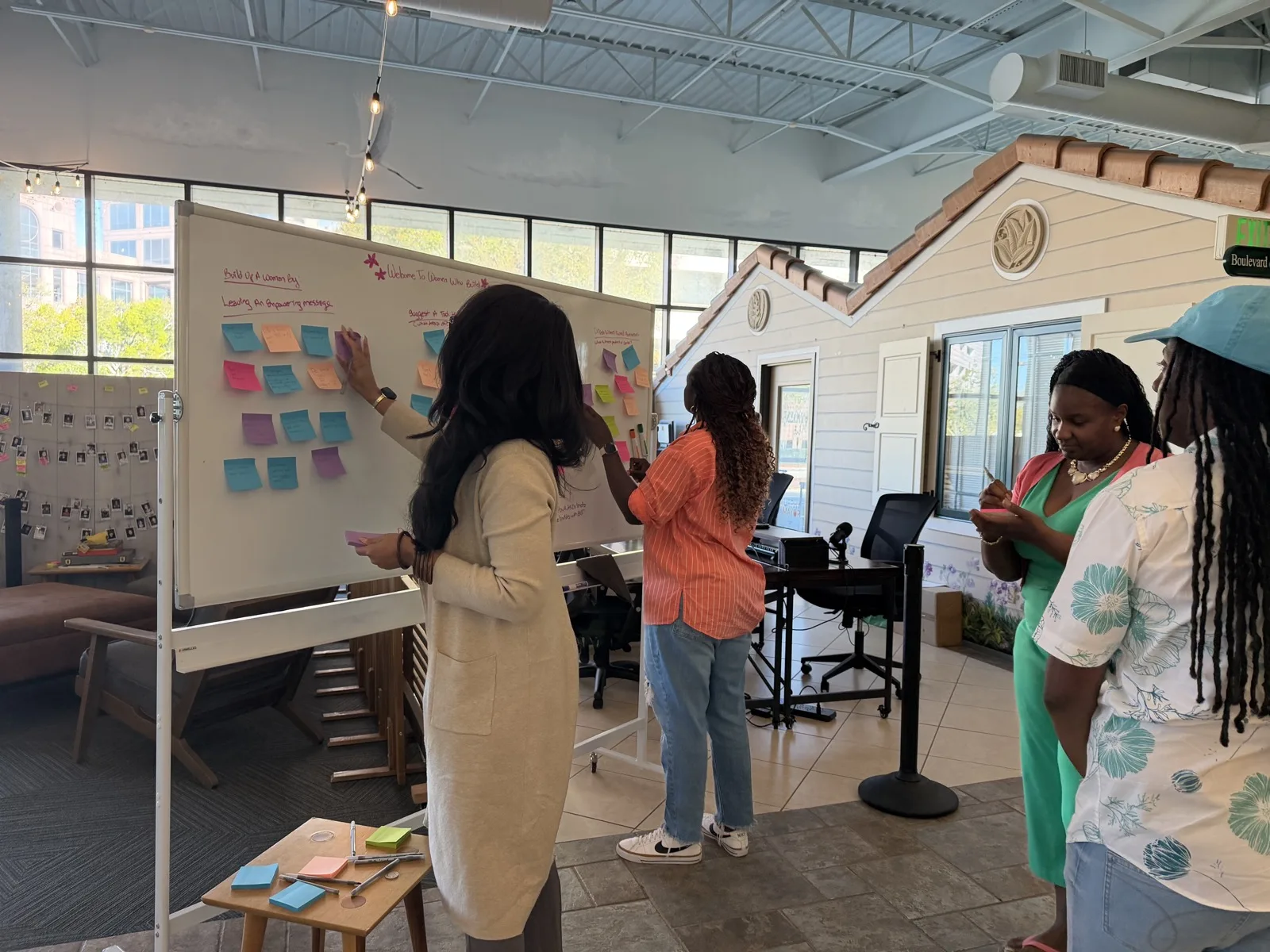 Participants adding sticky notes to a whiteboard during a Women Who Build session at Building Our Tech