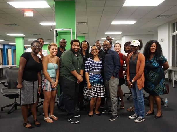 Around fifteen people posed together in a bright open-plan workspace after a monthly community meetup