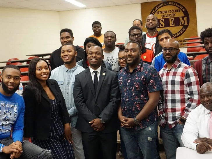 Students and Building Our Tech speakers grouped together in a Bethune-Cookman University room beneath a STEM banner