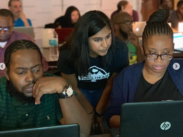 Three cohort members working at laptops during a Salesforce administrator training session