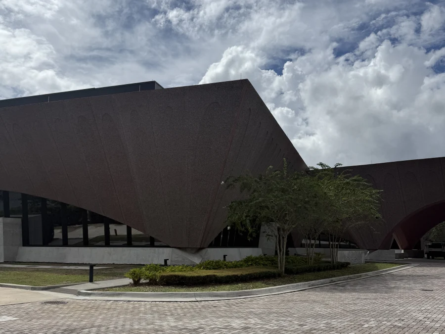 The Winter Park Events Center from the plaza, a long arched concrete roofline rising over a brick paved forecourt